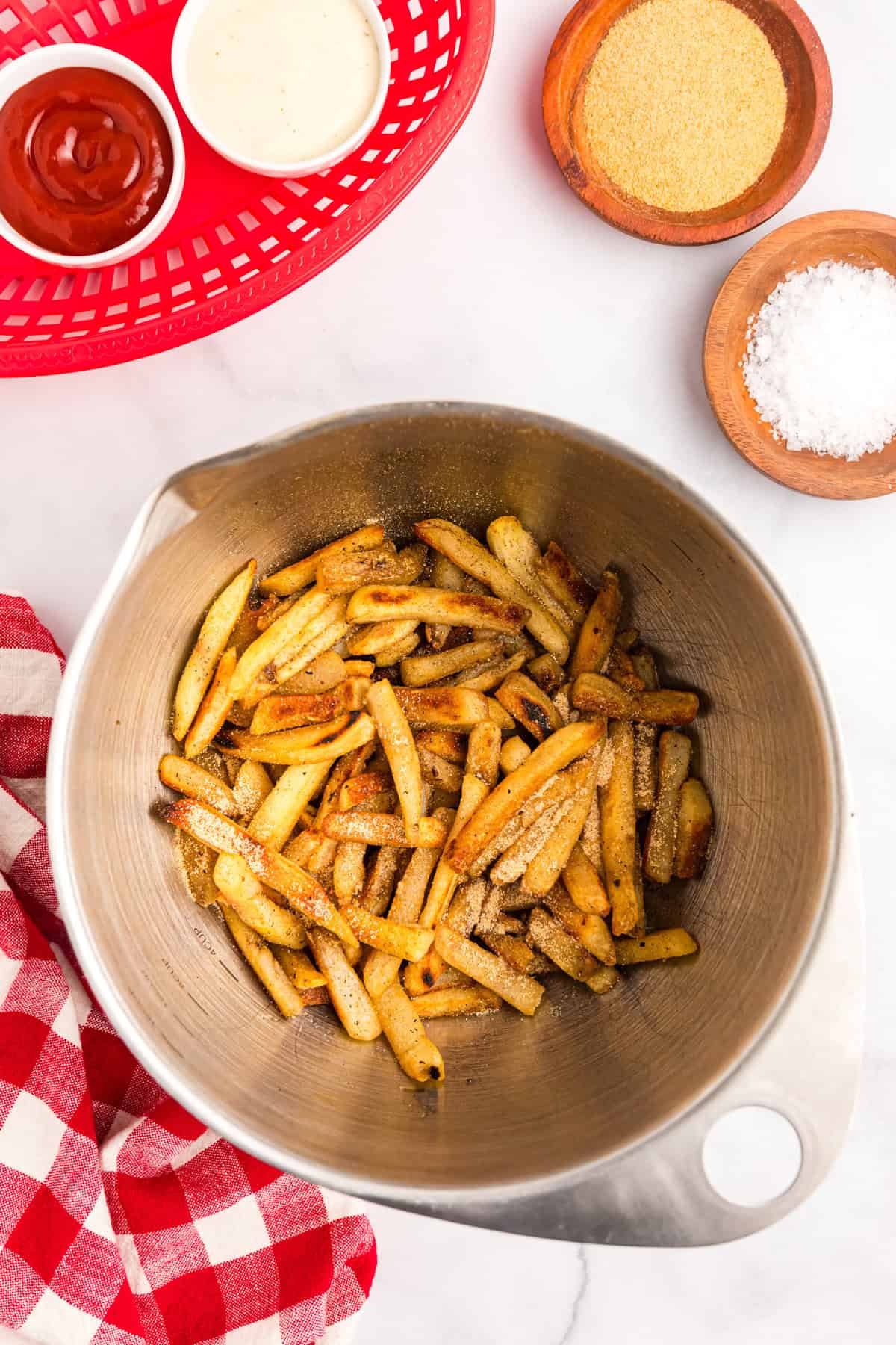 Transferring fries from griddle to metal bowl to toss in seasoned salt for Blackstone French Fries