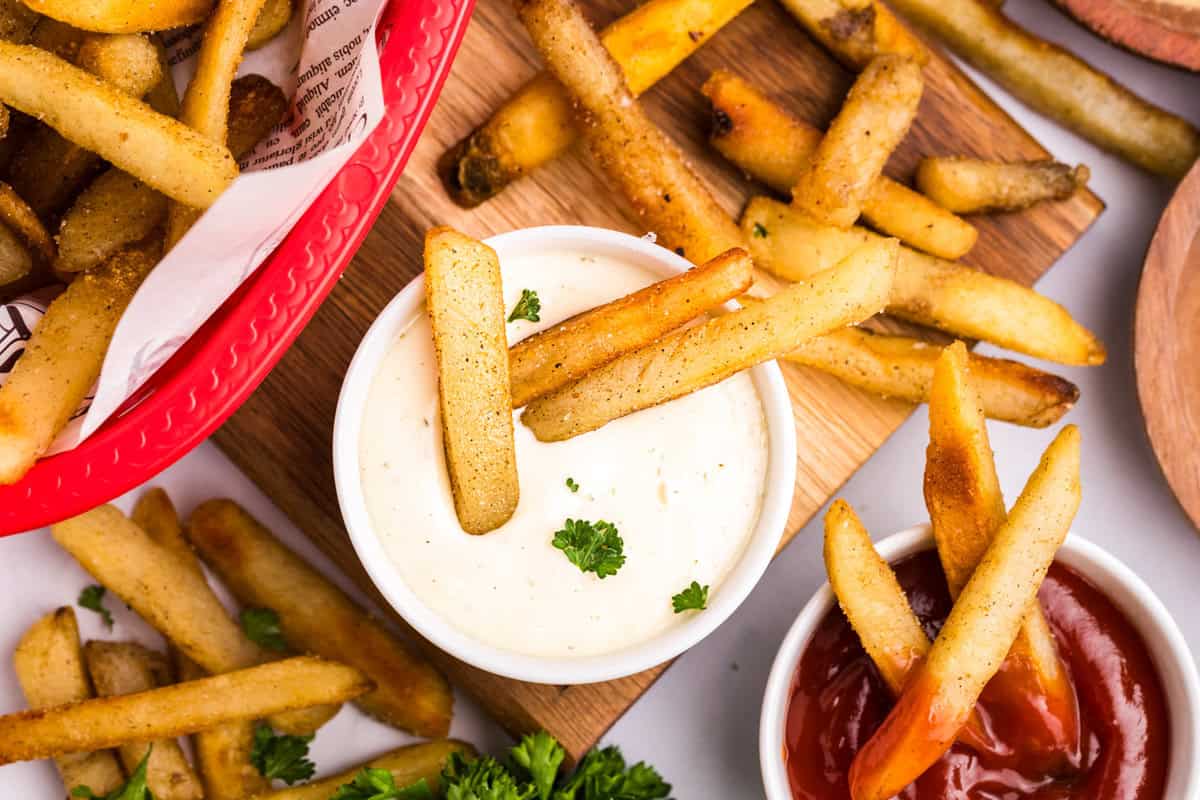 Blackstone French Fries spread about in baskets on tray with ketchup and ranch to dip