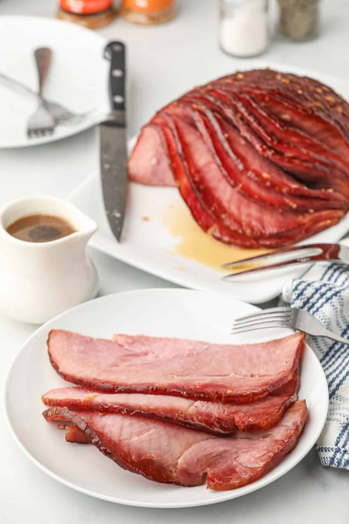 Double Smoked Ham with Glaze on serving plate with slices on white dinner plate