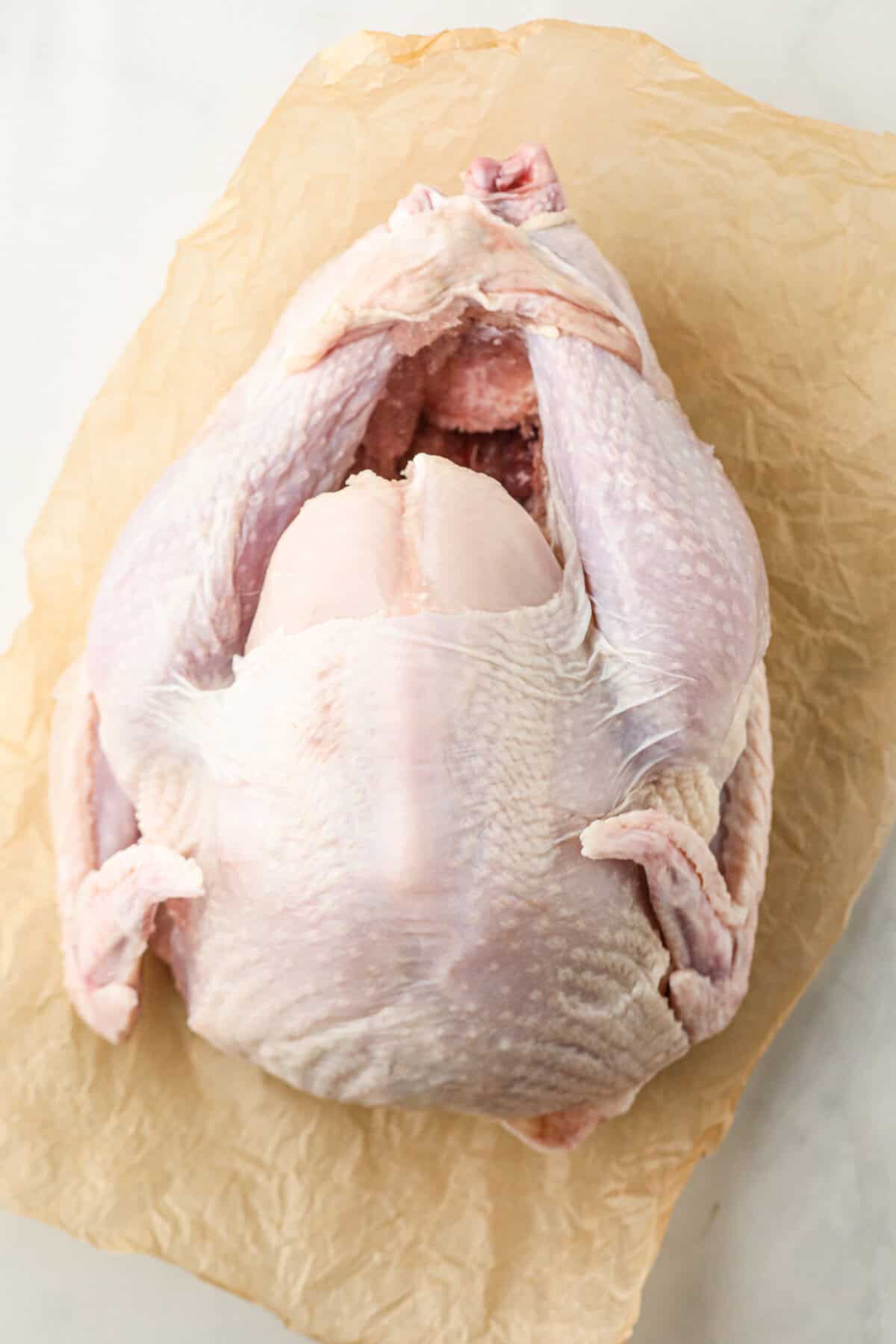 Overhead picture of raw whole turkey on a wooden cutting board.