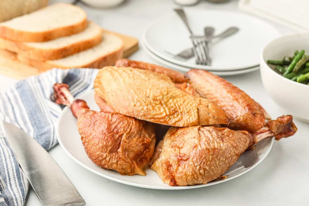 Partially cut up turkey on a white serving plate.