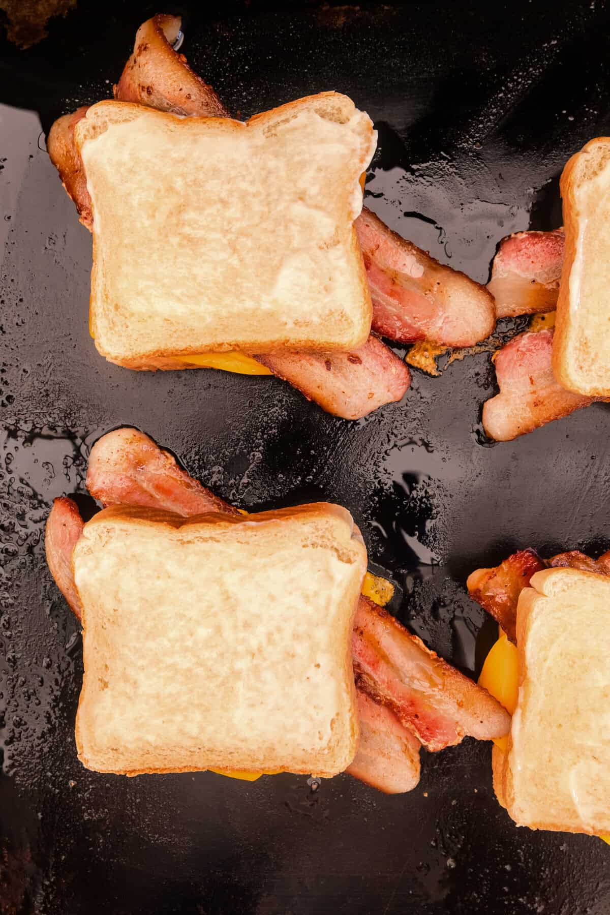 Overhead picture of assembled grilled cheeses on the Blackstone not fully cooked.