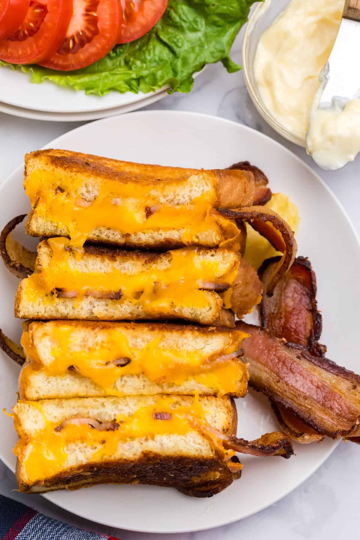 Overhead picture of a white plate with Blackstone Grilled Cheese sandwiches cut in half on it. 