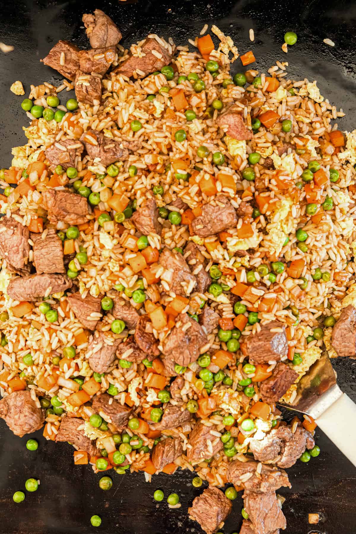 Cooked Blackstone Fried Rice with a metal spatula scooping it up.