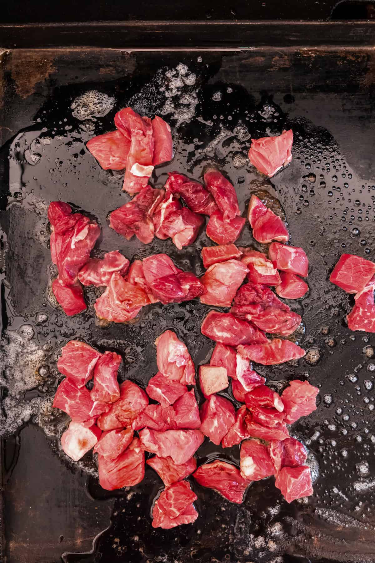Raw cubed steak on the Blackstone.