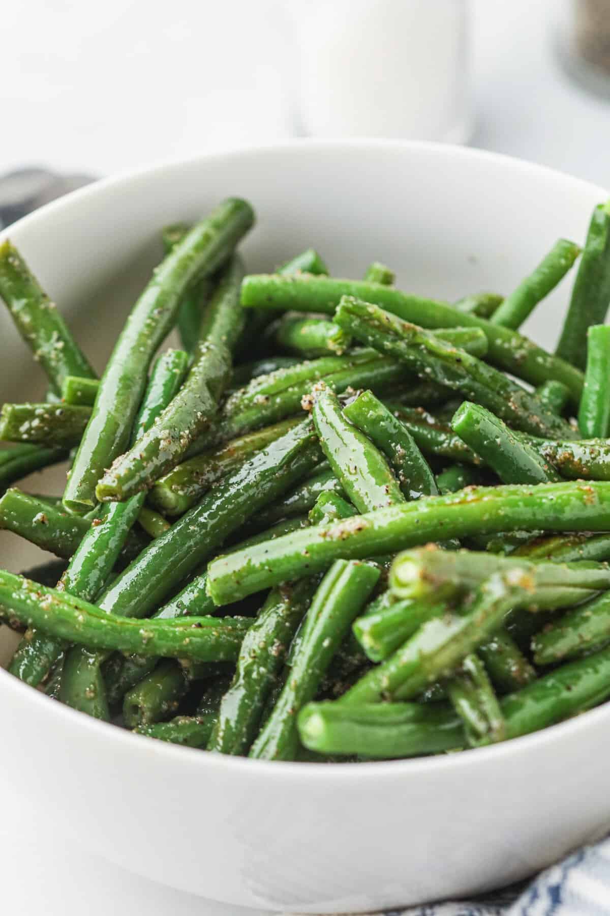 White bowl with grilled green beans in it.