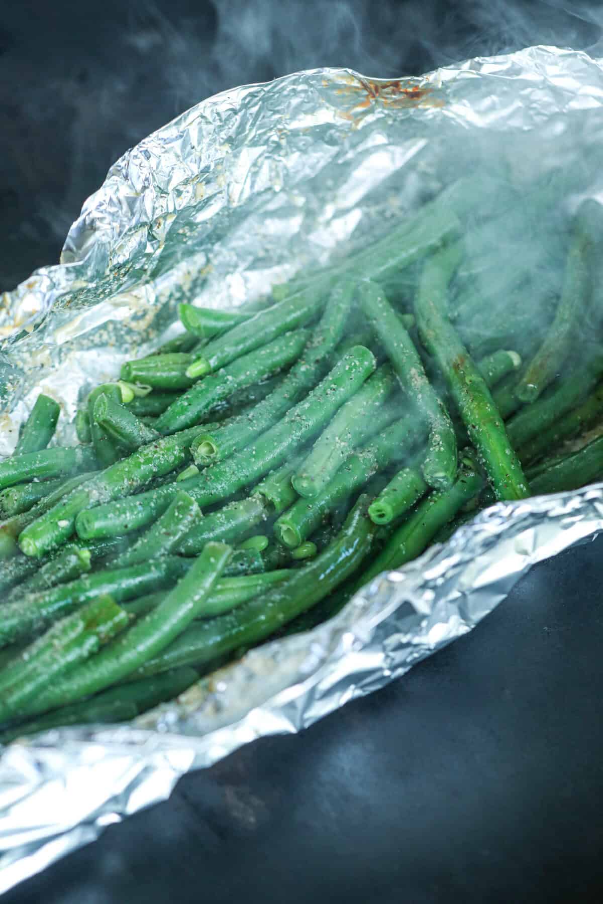 Close up of cooked green beans in foil on grill