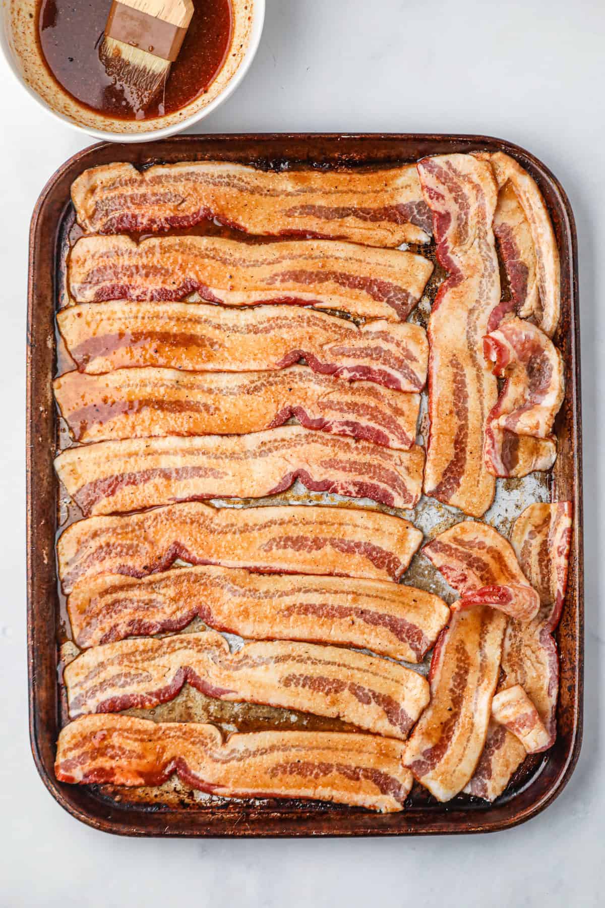 Overhead picture of marinated bacon on a metal pan.