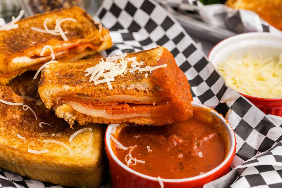 picture of 3 halves of blackstone pizza grilled cheese with one half dipped in pizza sauce.