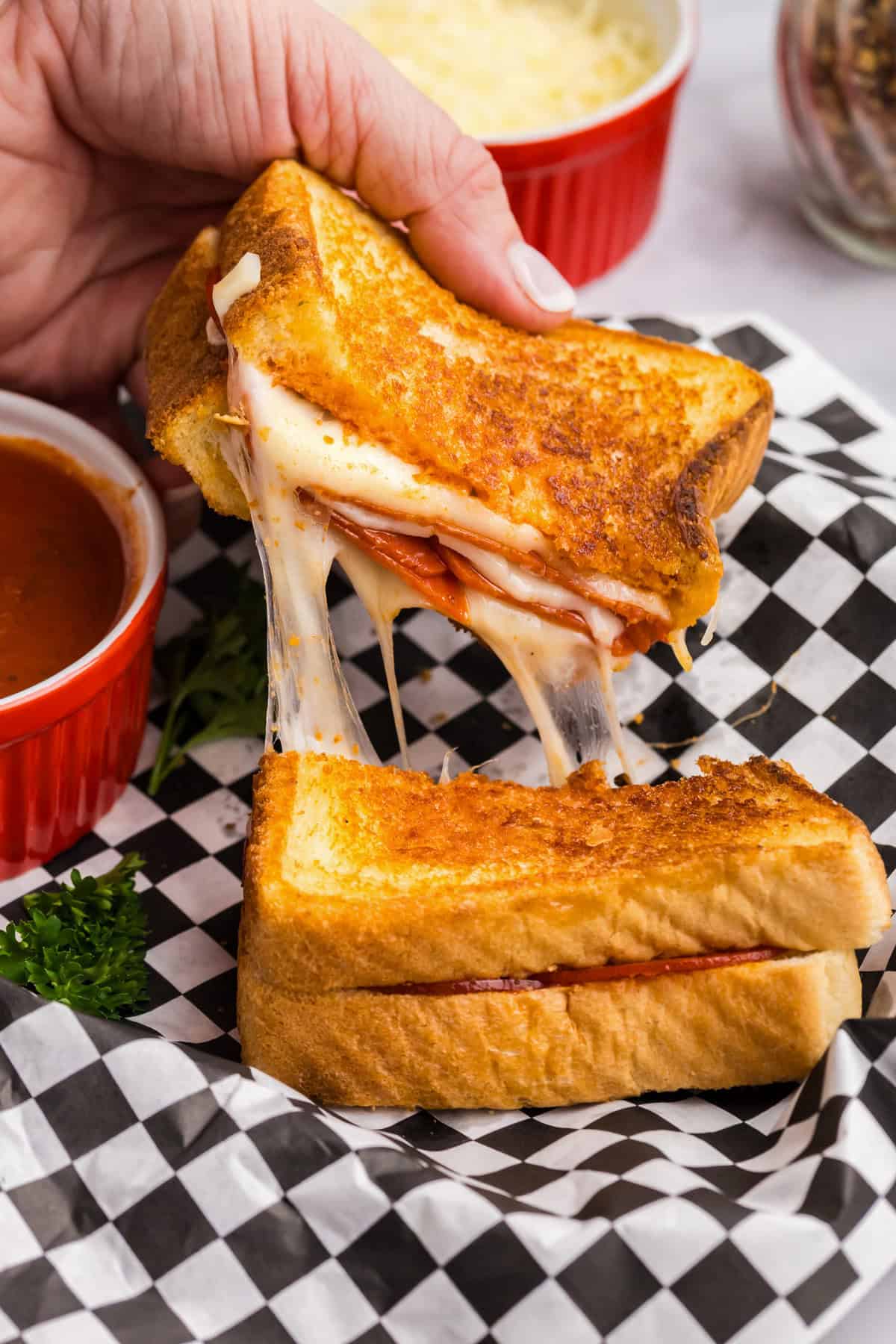 Picture of a completed Blackstone Pizza Grilled Cheese being pulled apart with cheese stringing between the two halves. 