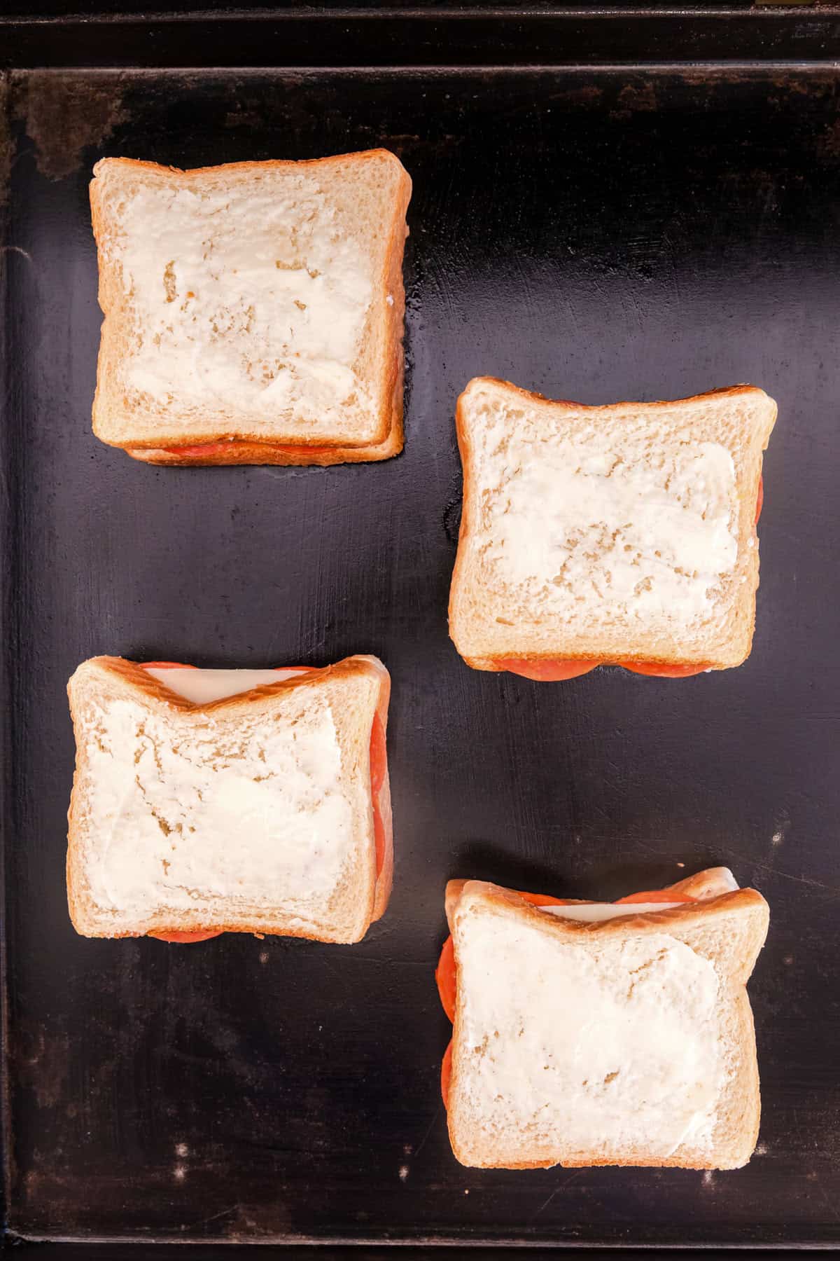 Overhead picture of buttered Blackstone Pizza Grilled Cheese on the Blackstone, not yet cooked.