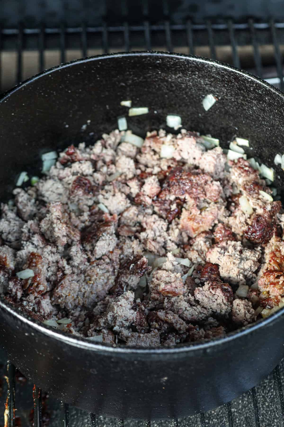 Close up image of sausage and ground beef in a cast iron pot.