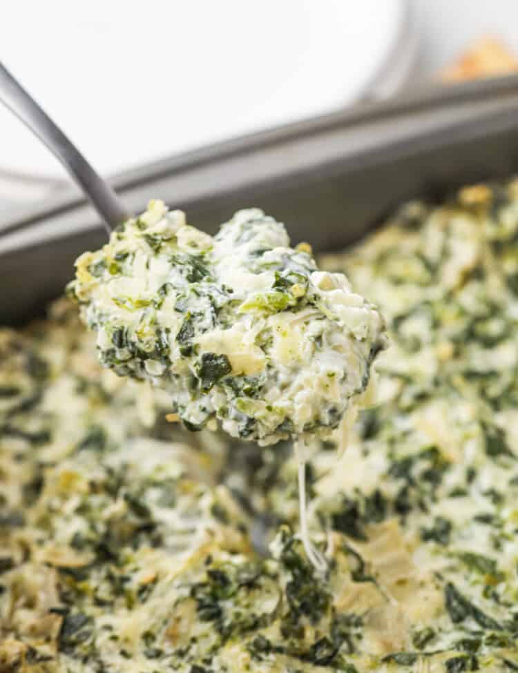 Cooked Smoked Spinach Artichoke Dip being scooped up by metal spoon.