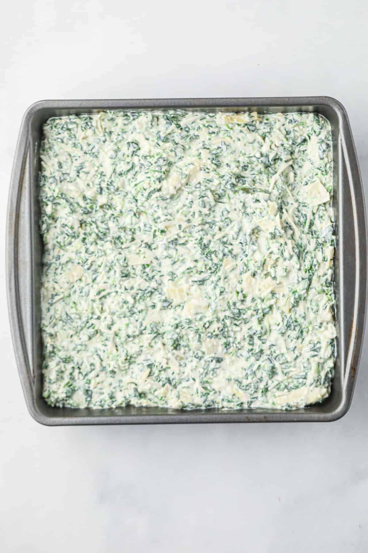 Overhead picture of uncooked Smoked Spinach Artichoke ingredients in a metal pan.