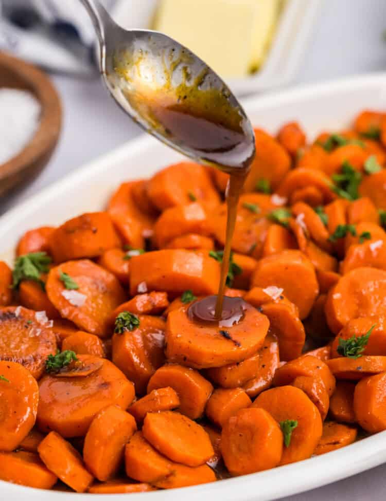 Close up of spoon drizzling glaze on carrots.