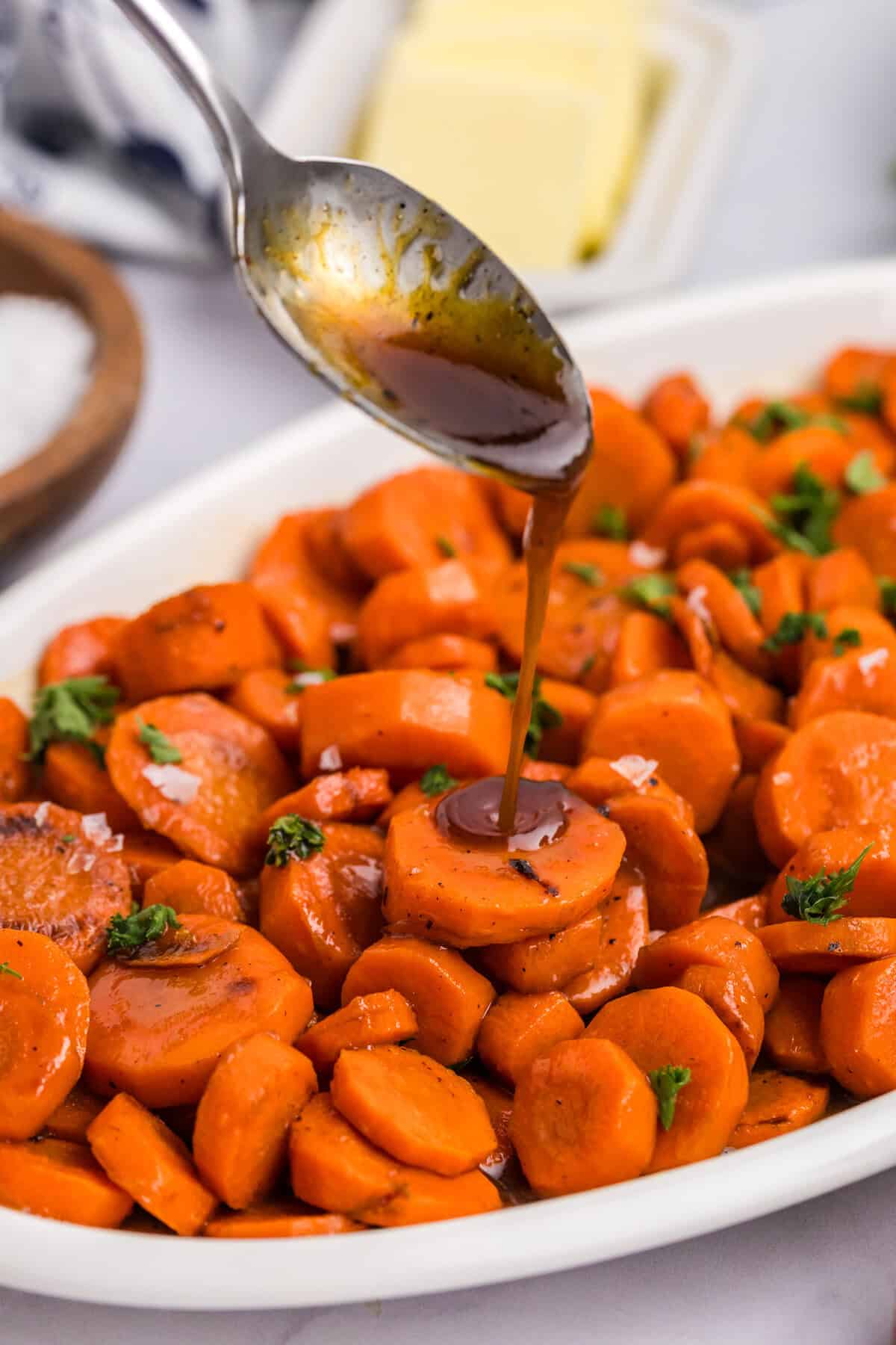 Close up of spoon drizzling glaze on carrots. 