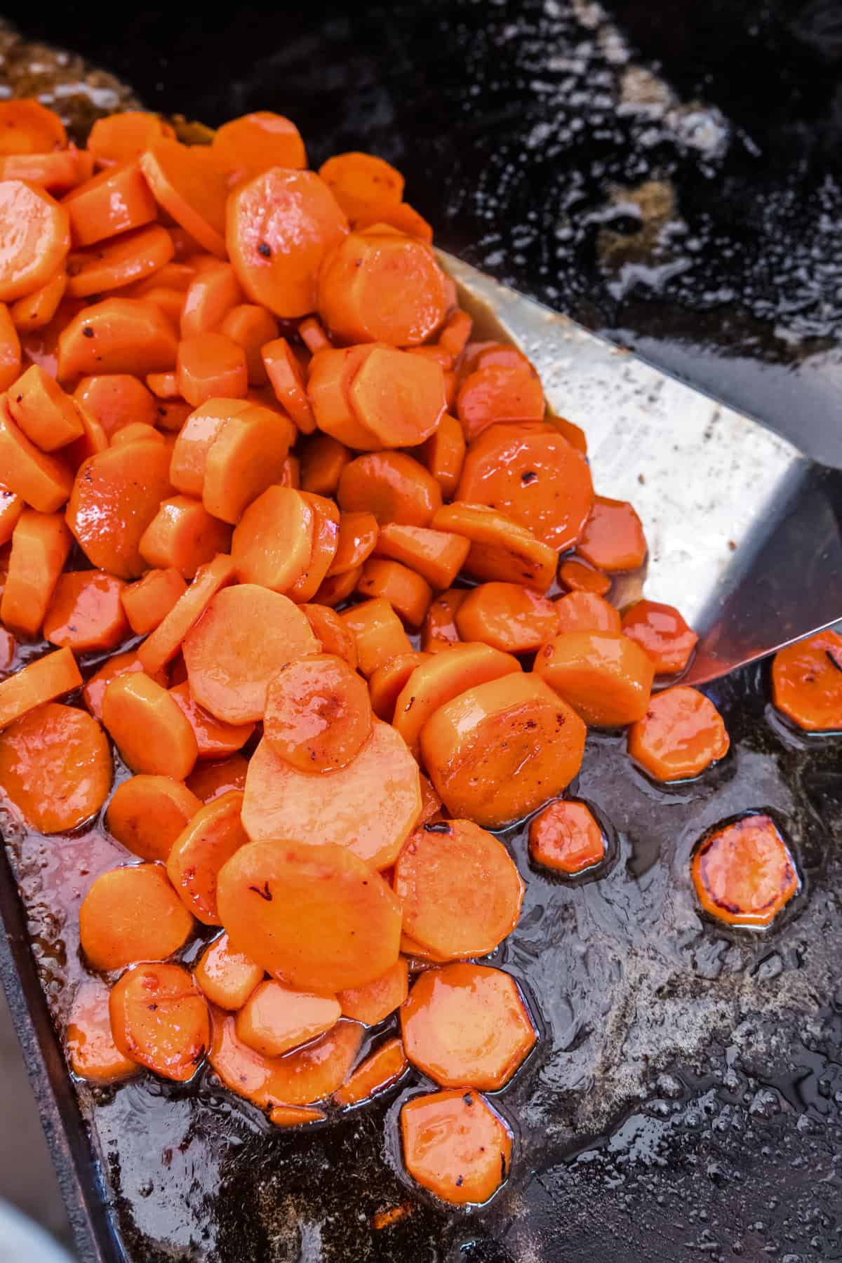 Close up of 2 spatulas scooping carrots on the blackstone.