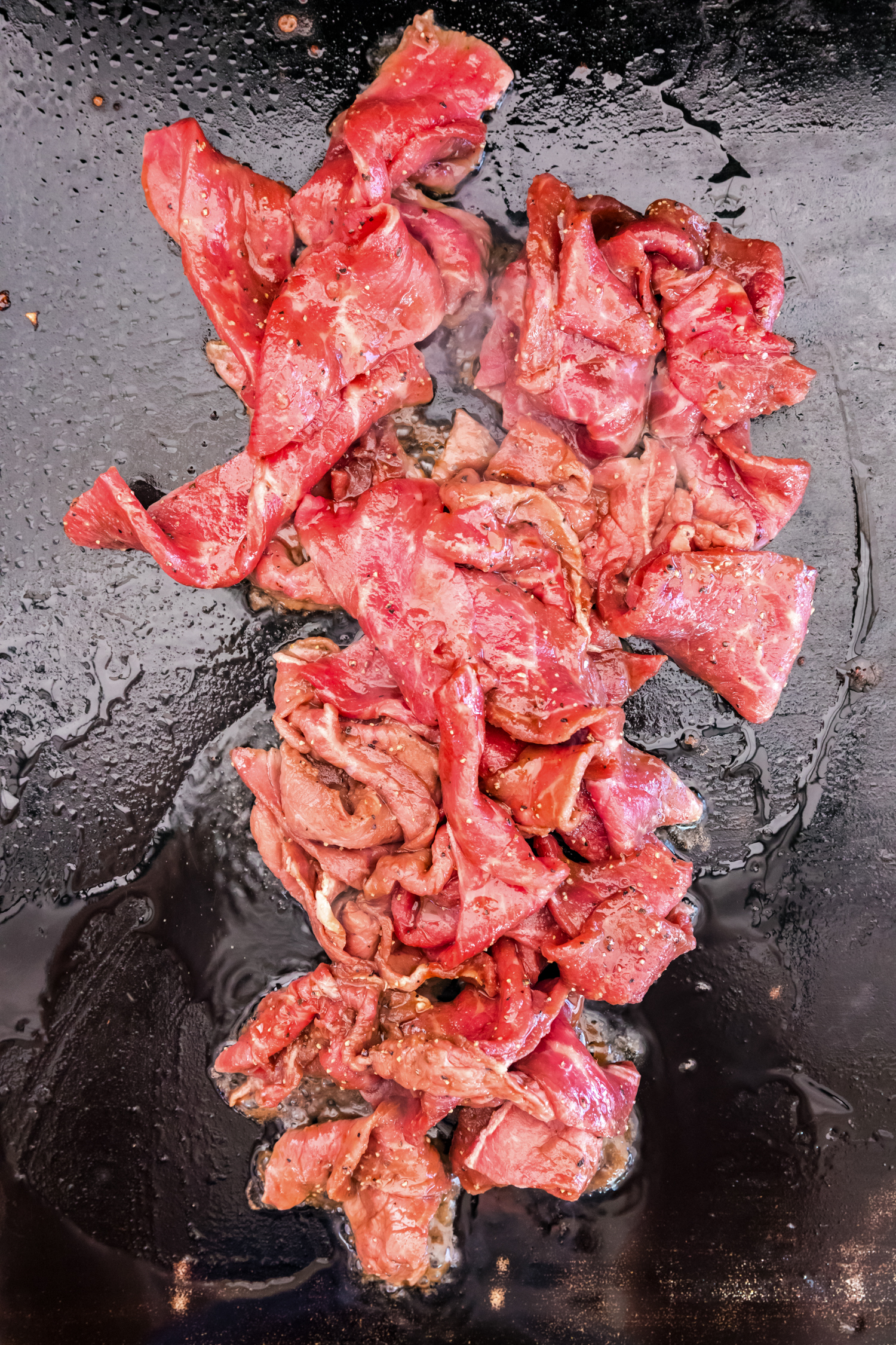 Overhead picture of raw steak on the blackstone.