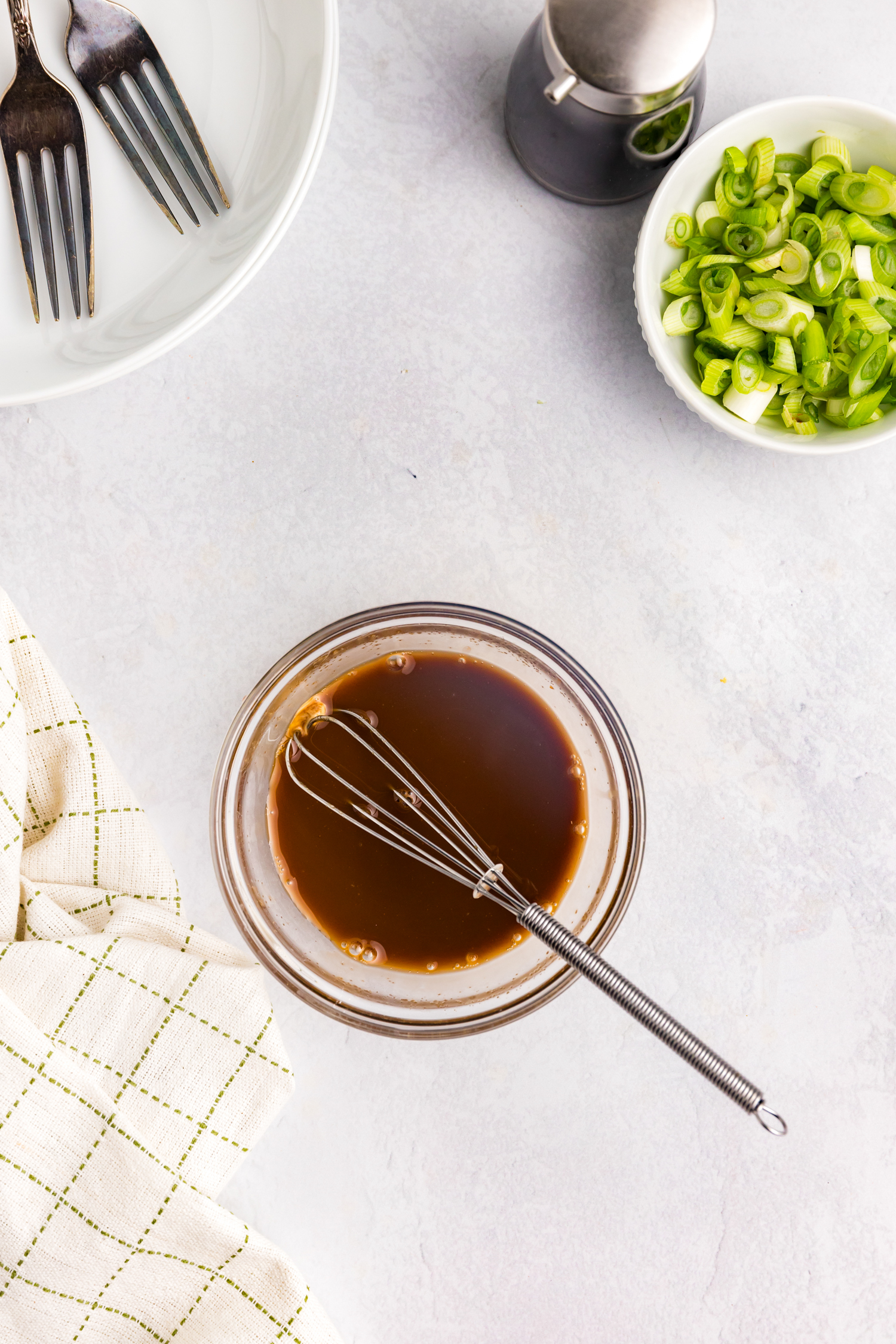 Overhead picture of glass bowl with sauce and a whisk in it.