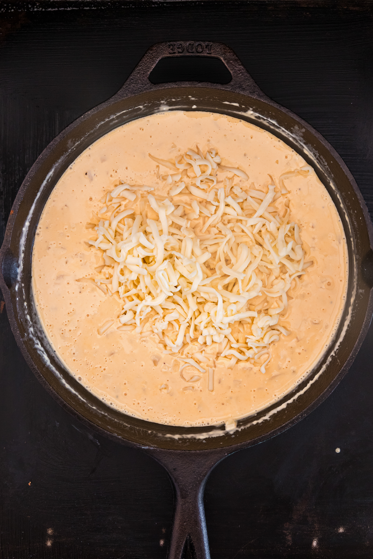 Overhead picture of queso with shredded cheese unmixed.