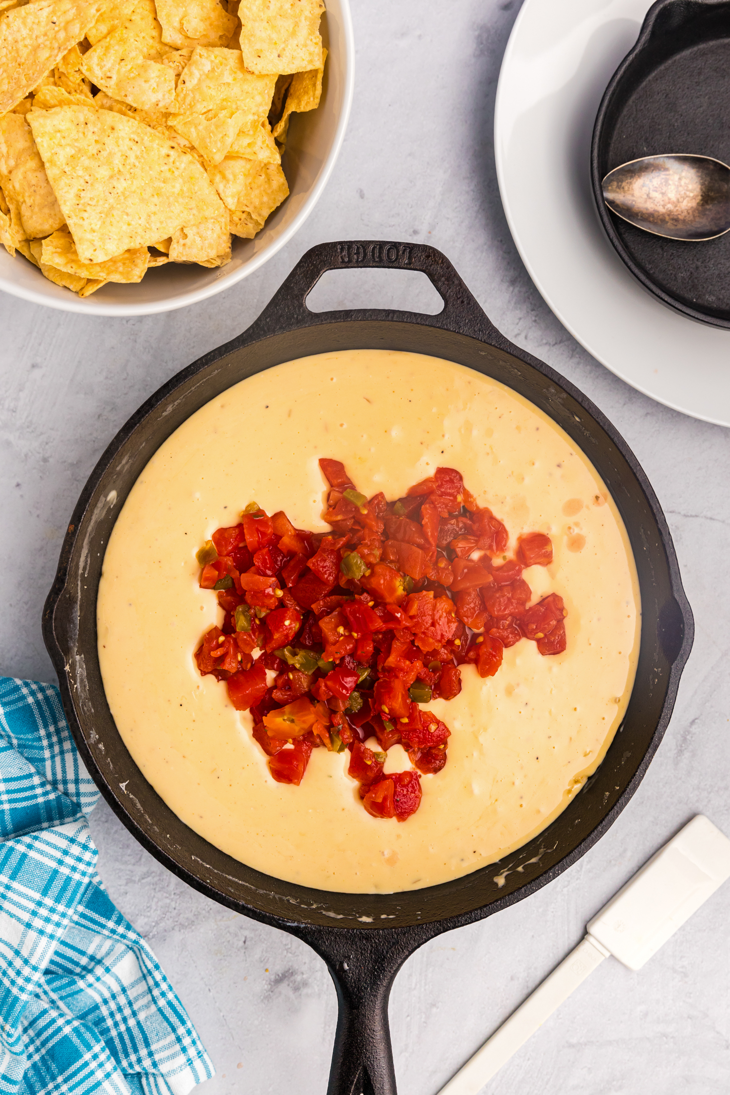 Overhead picture of queso with rotel unmixed, in a cast iron skillet.