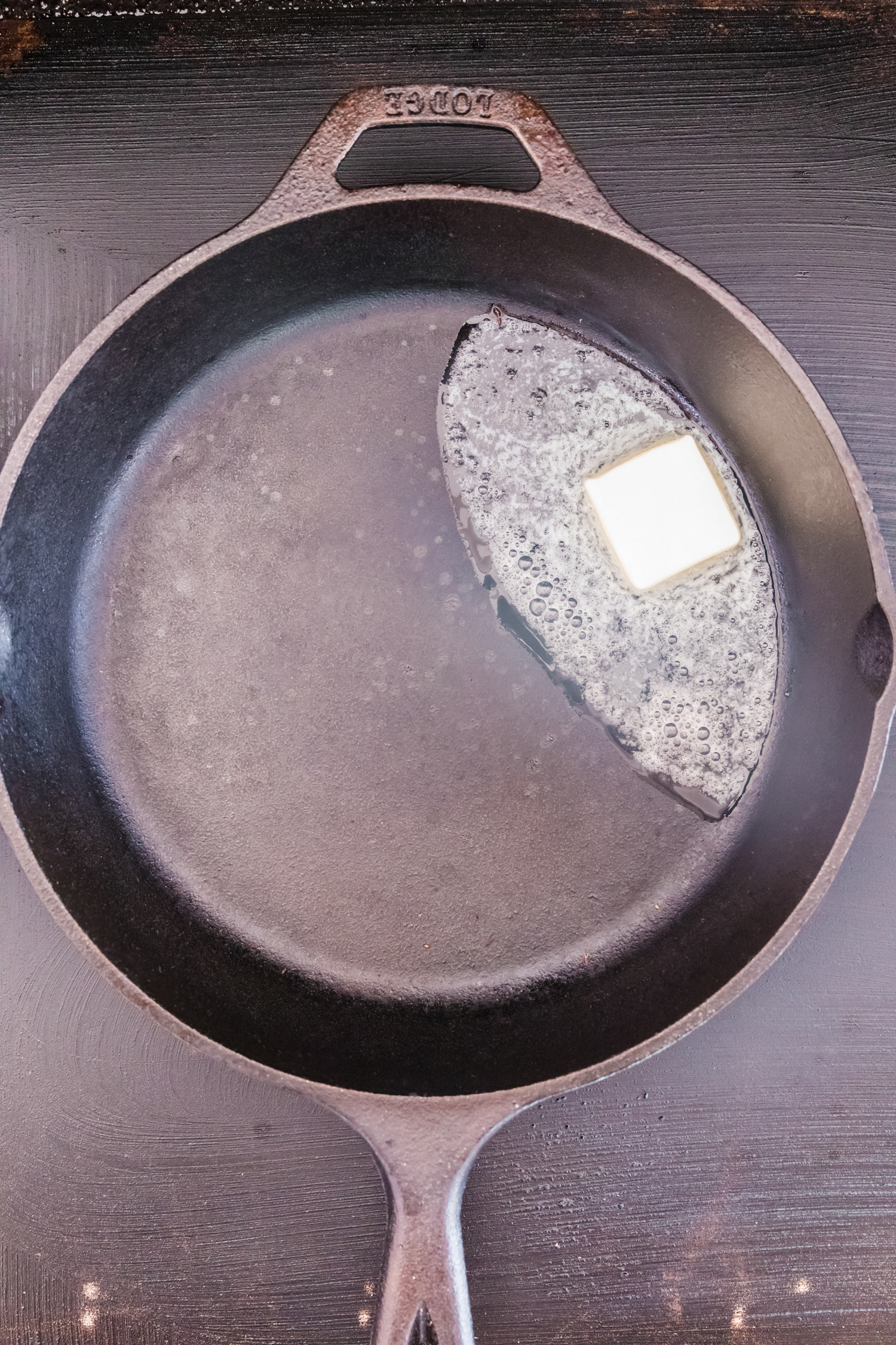 Overhead picture of butter melting in a cast iron skillet.
