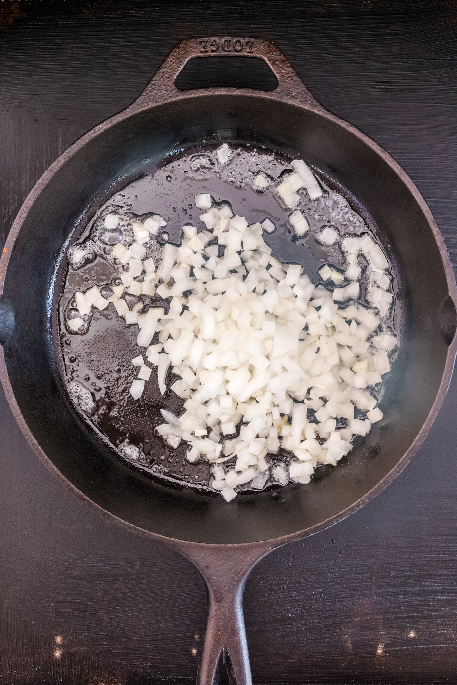 Overhead picture of raw onions in a cast iron skillet.