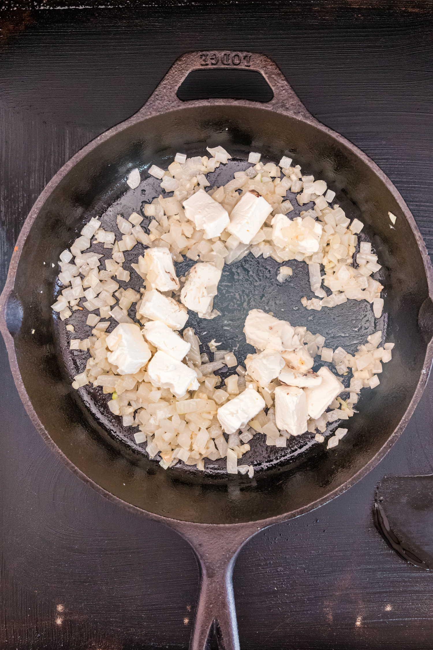 Overhead picture of onions and cream cheese in a cast iron skillet.
