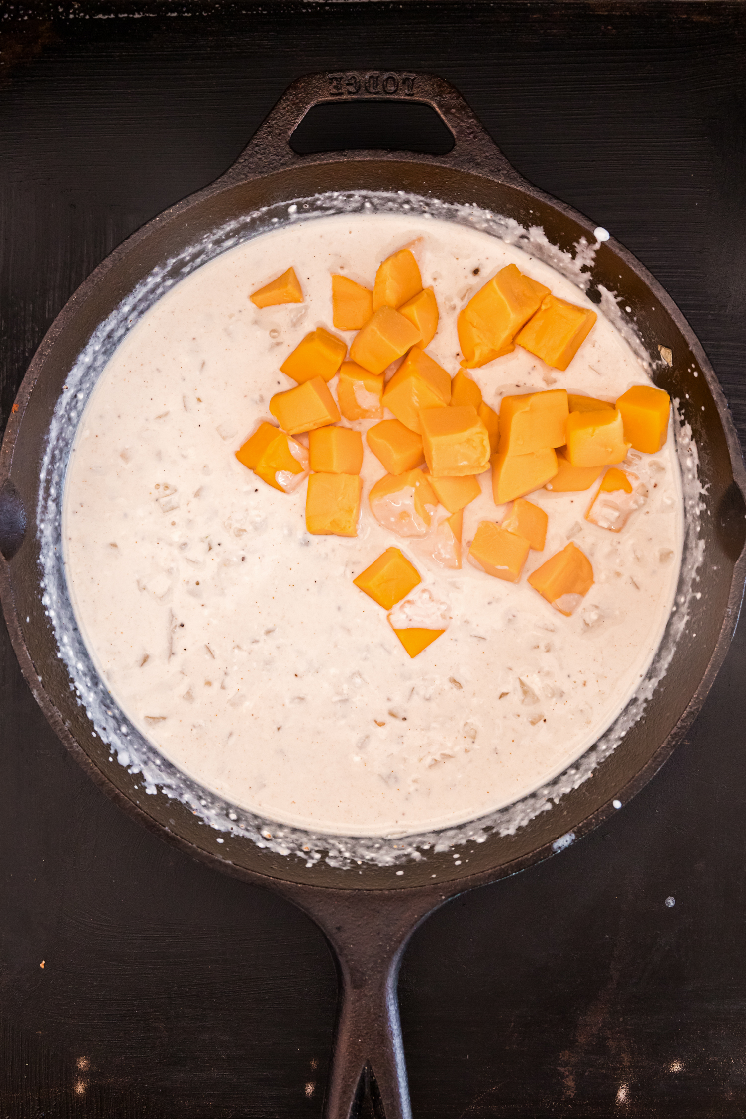 Overhead picture of queso with cubed cheese in it unmixed.