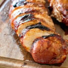 Grilled Asian Pork Tenderloin cut into slices on cutting board.