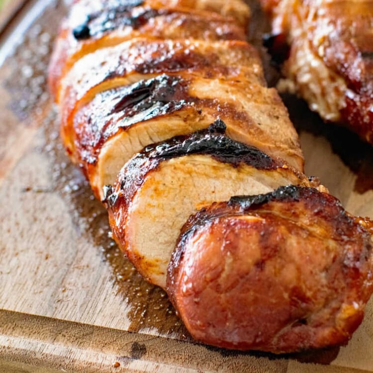 Grilled Asian Pork Tenderloin cut into slices on cutting board.