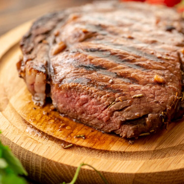 Cooked steak on wood platter made with Balsamic Steak Marinade