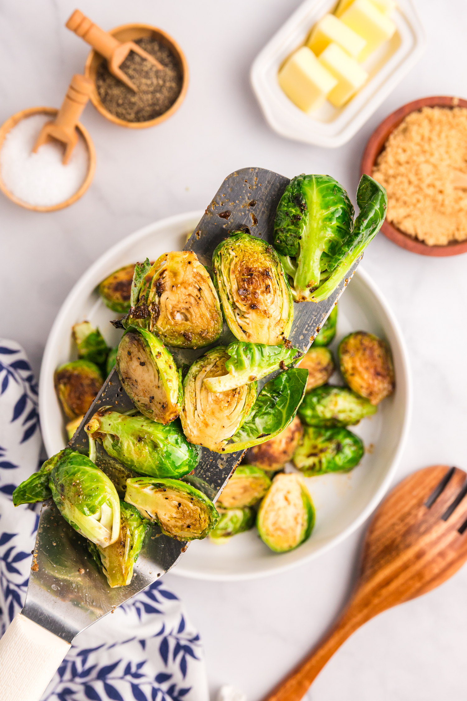 A close-up of cooked Brussels sprouts on a metal spatula, showing a crispy and caramelized surface.