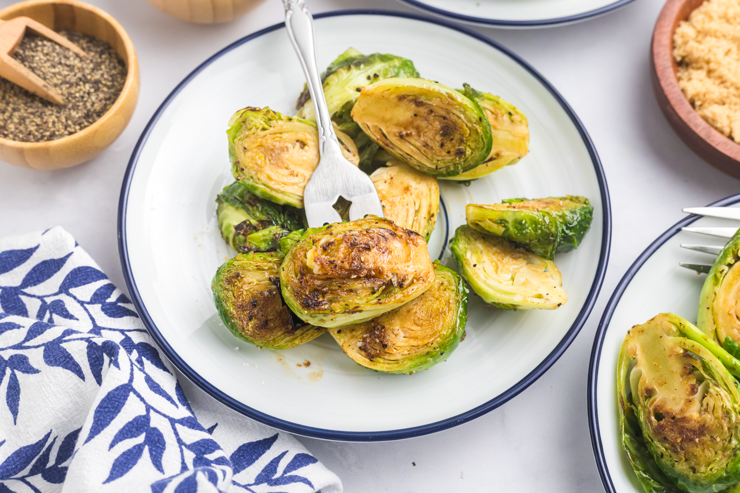 Plated roasted Brussels sprouts served on a white dish with a fork, ready to eat.