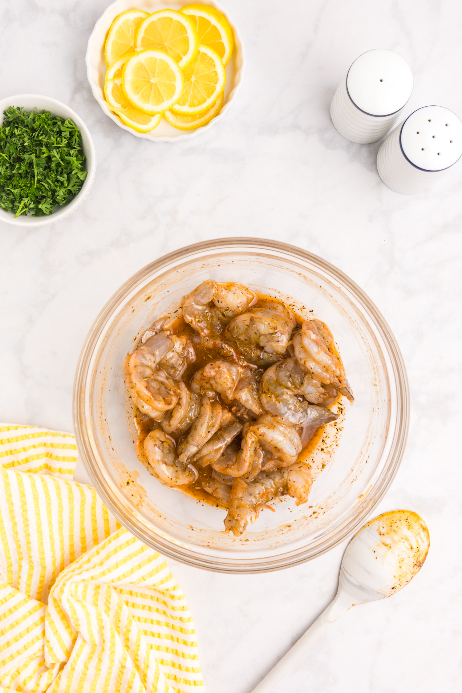 The shrimp have been fully coated in the marinade and mixed thoroughly in the bowl.