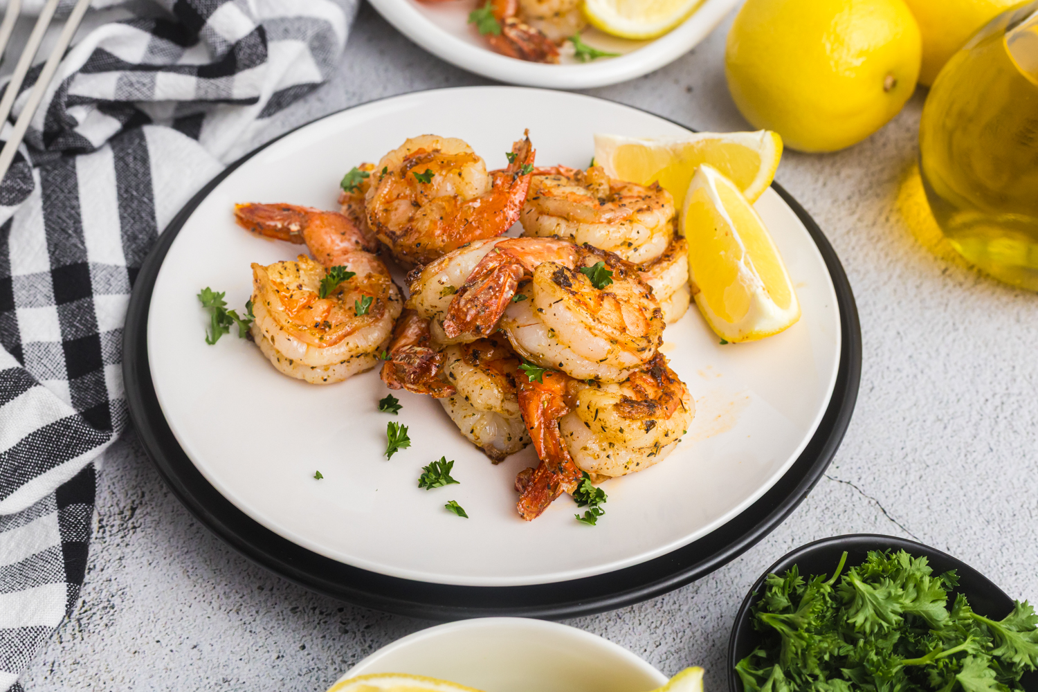 Cooked shrimp served on a white plate with lemon wedges and parsley, ready to eat.