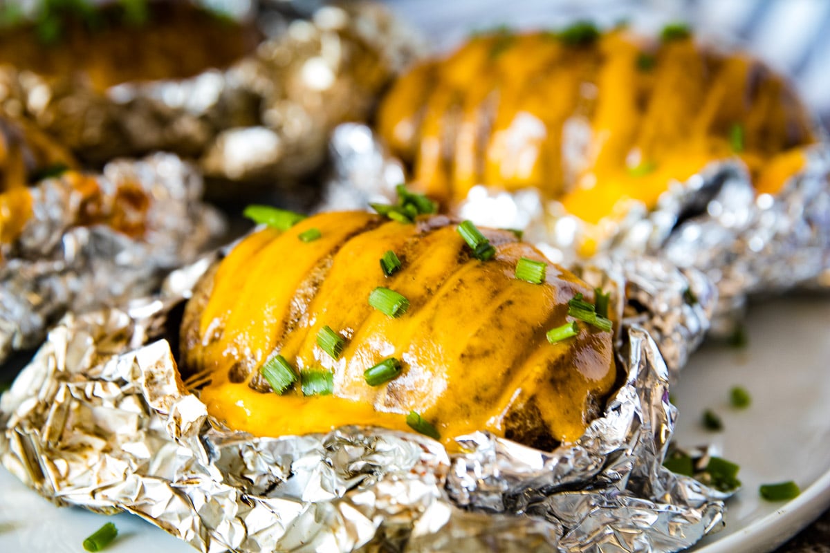 Smoked Hasselback Potatoes laying on foil with melted cheese in them