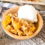 Smoked Peach Dump Cake in a wooden bowl with a scoop of ice cream