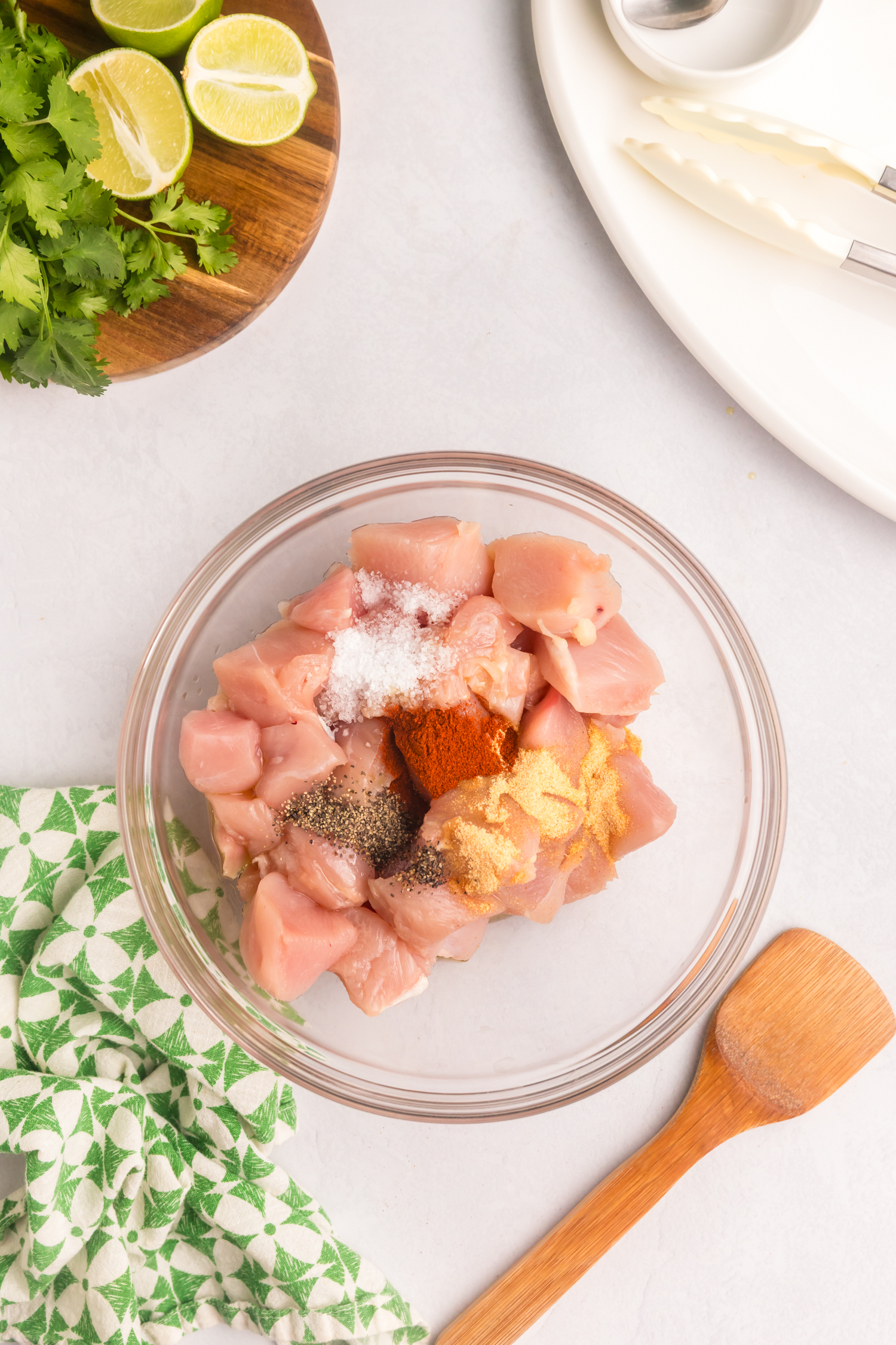 Additional seasonings including paprika added to the bowl of raw chicken, enhancing the marinade preparation.
