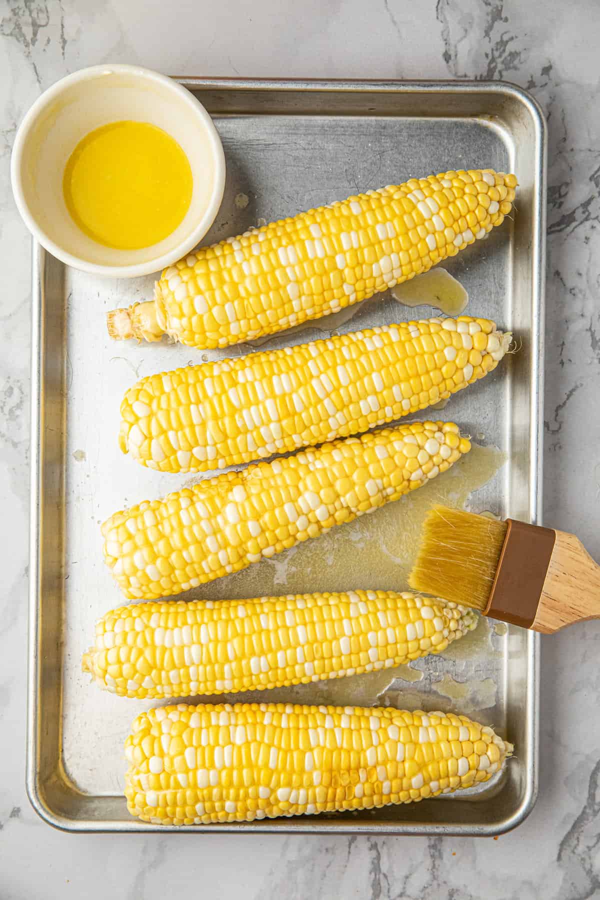 Corn arranged on cooking sheet ready to be buttered