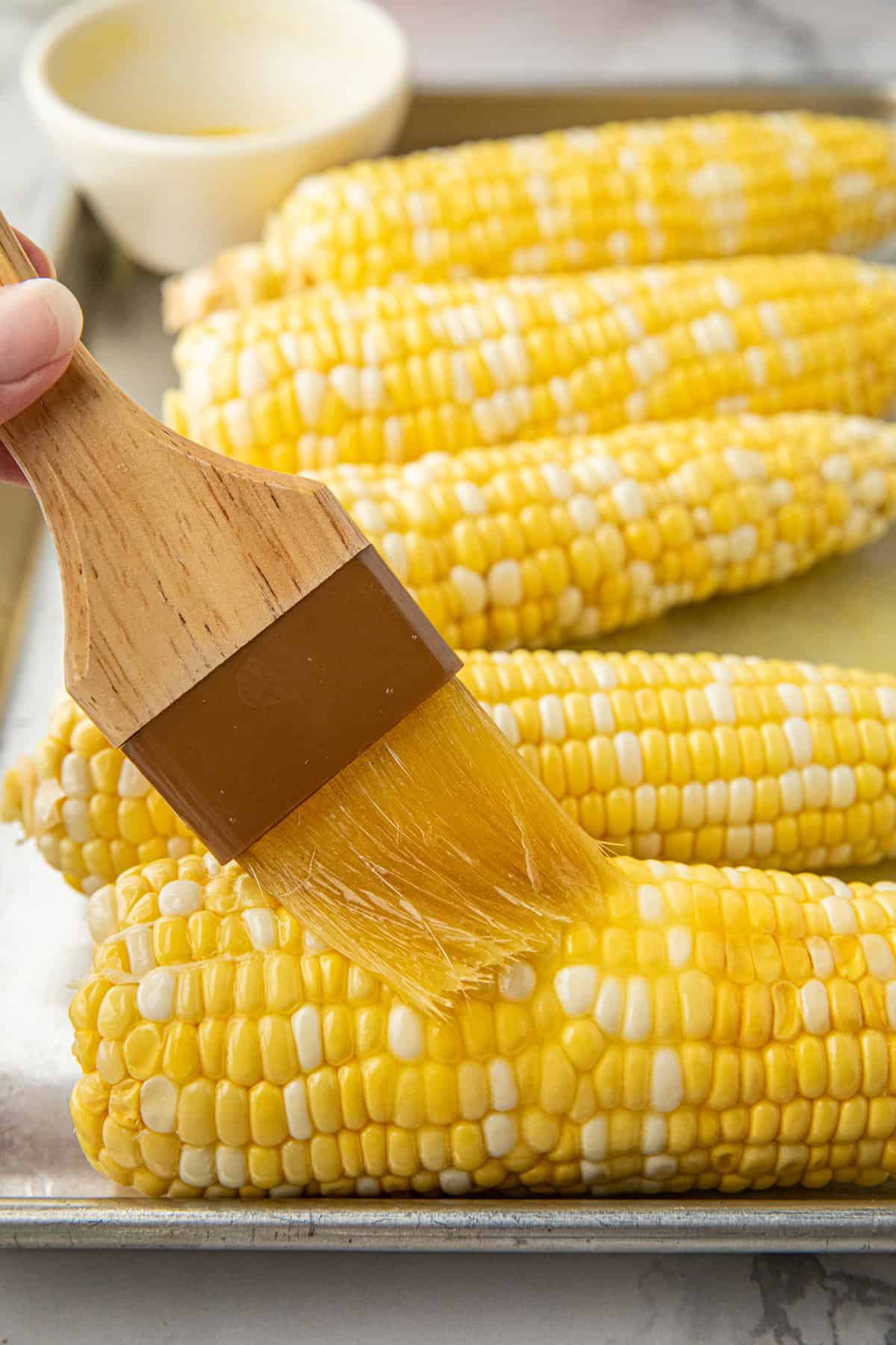 Brushing on butter to corn cobs for Smoked Corn on the Cob recipe
