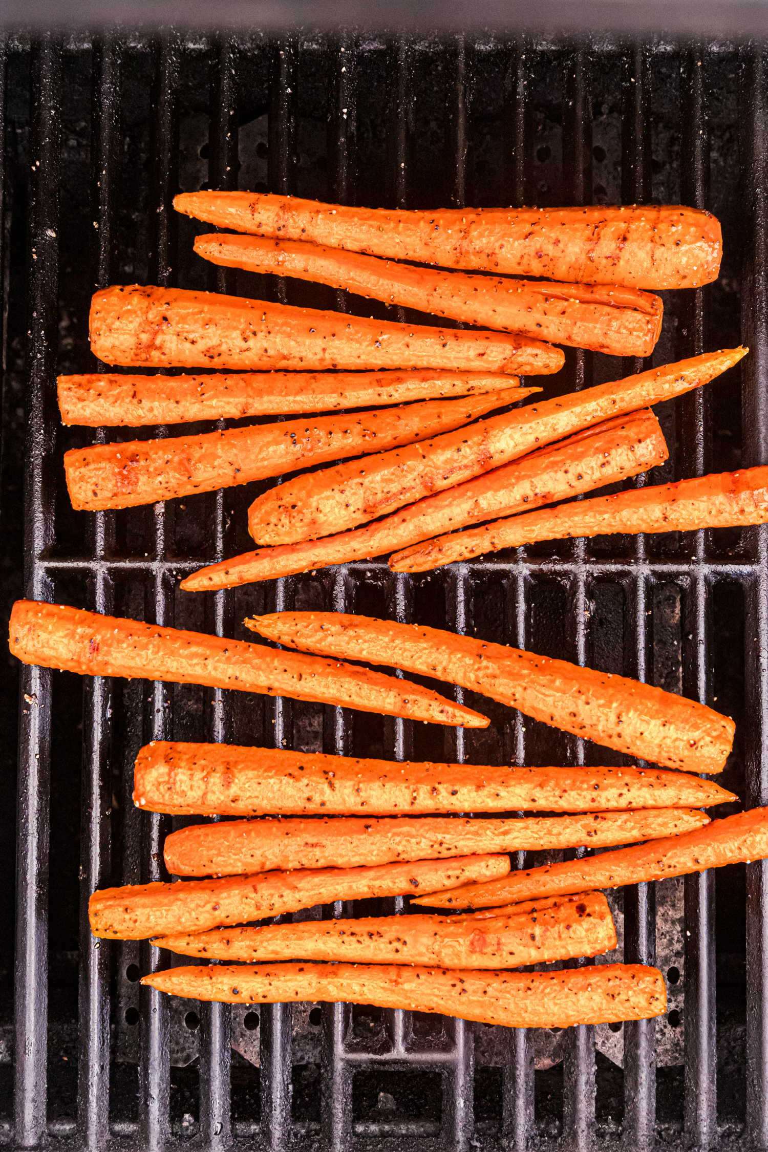 Carrots on the grill starting to show light grill marks as they cook.