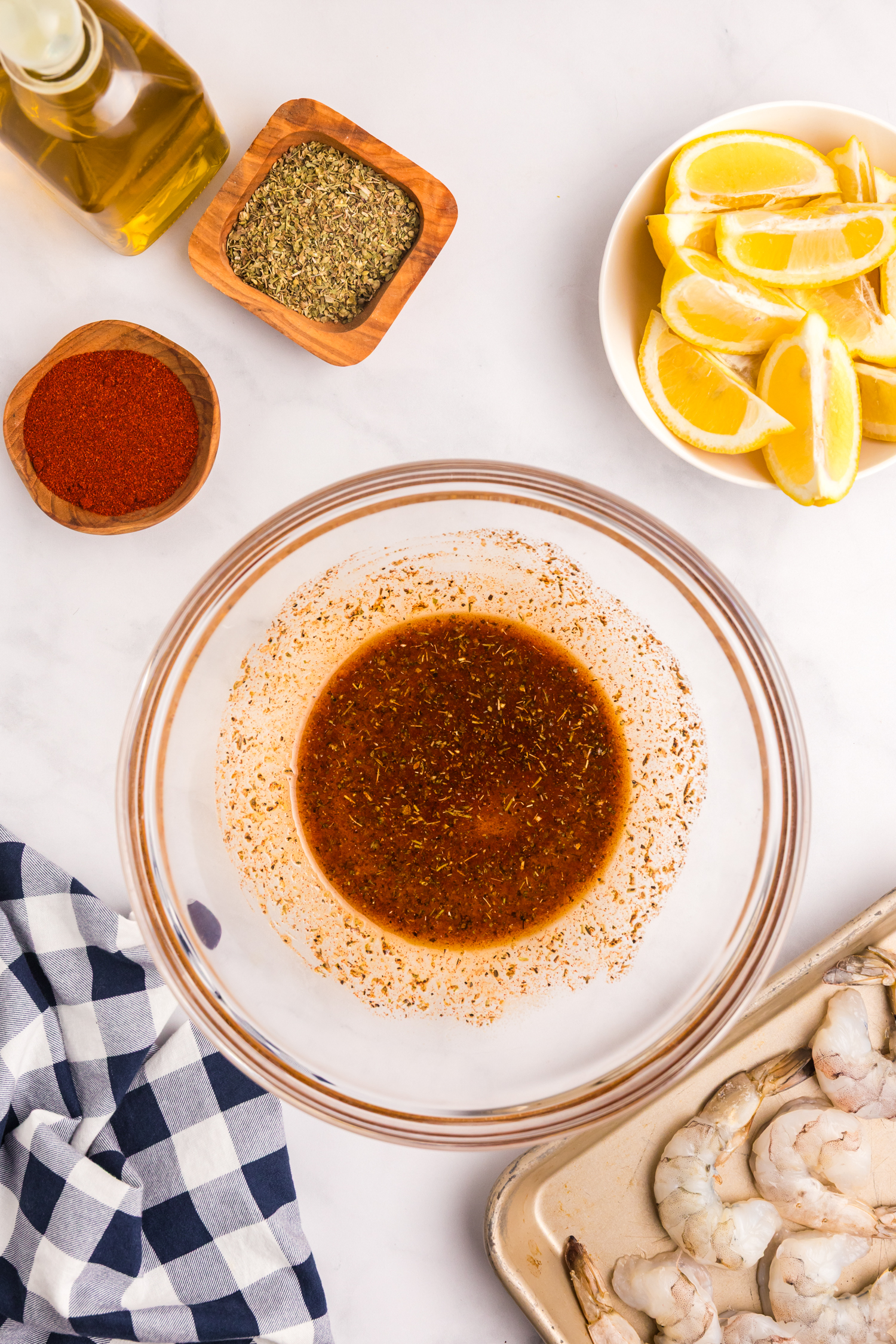 The spice mixture in the glass bowl fully combined into a marinade with a deep reddish-brown color.
