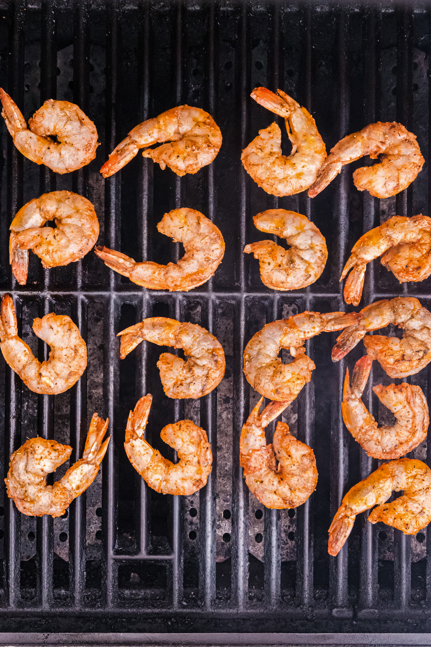 Marinated shrimp placed on a hot grill, beginning to cook with a light sear.