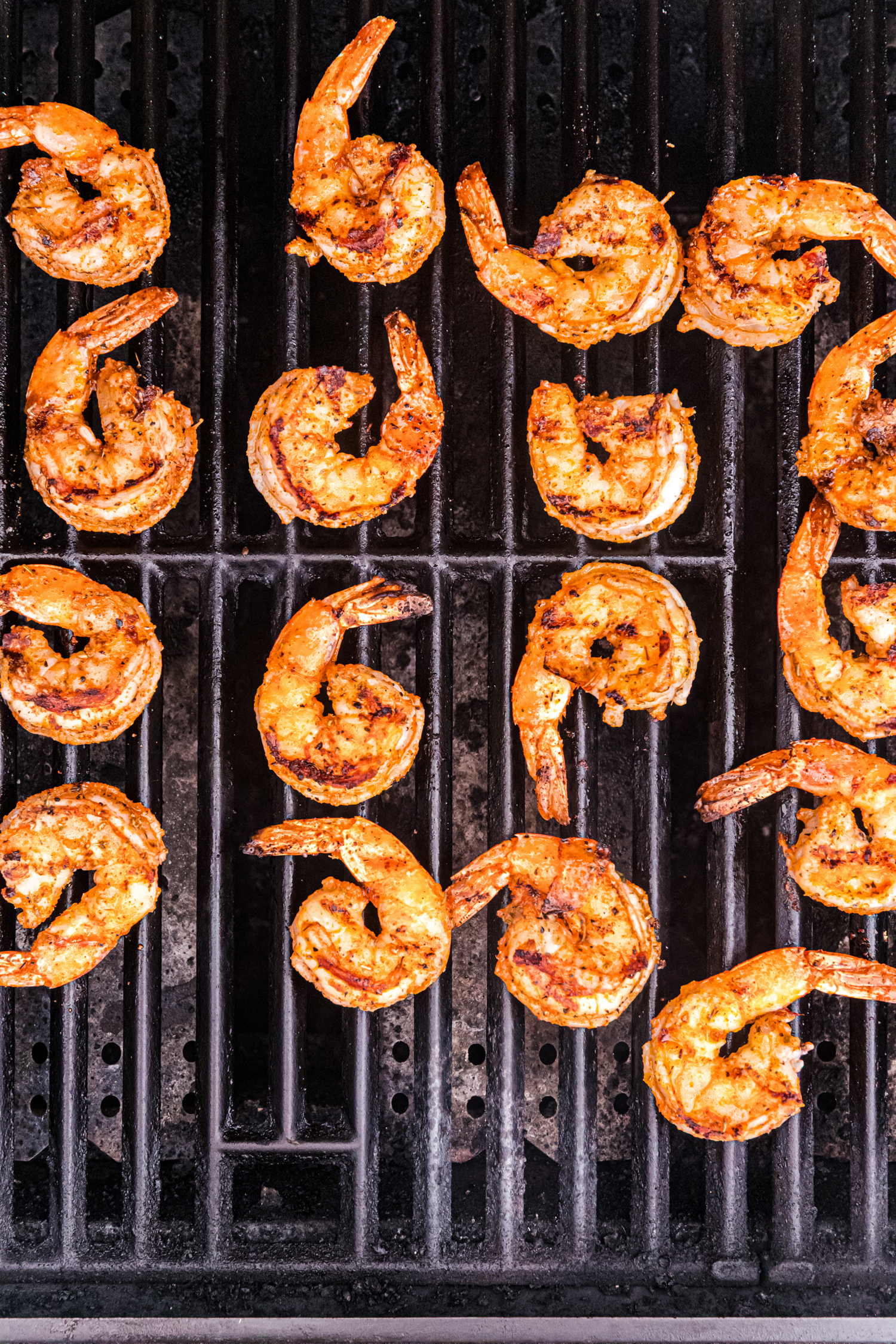 Grilled shrimp showing more pronounced grill marks and browning, indicating they are nearly done.