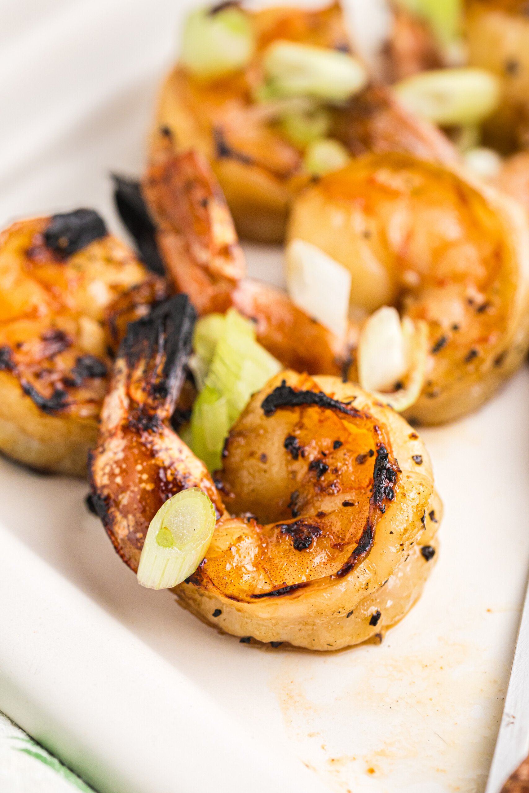 Close-up of grilled shrimp garnished with chopped green onions, ready to serve.