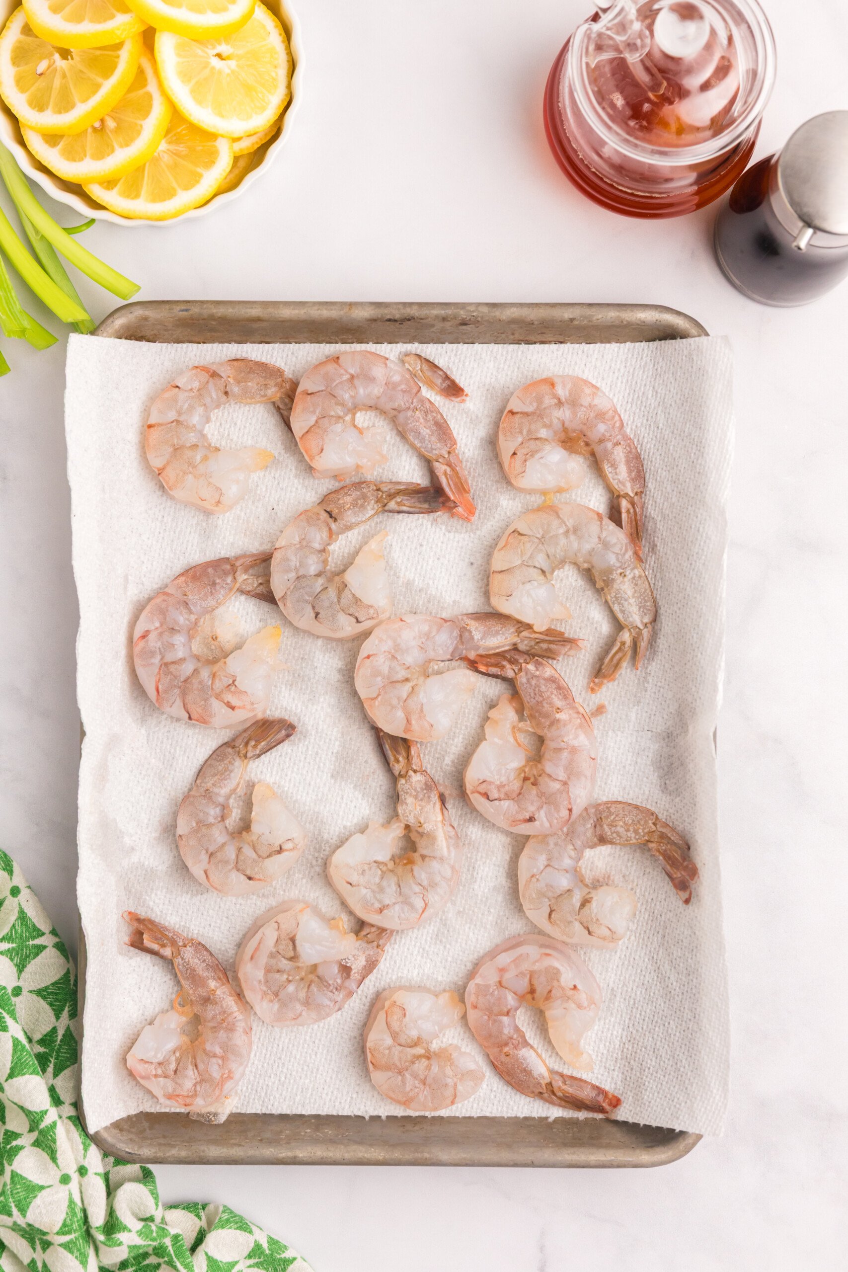 Raw shrimp laid out on a paper towel-lined baking sheet to dry.