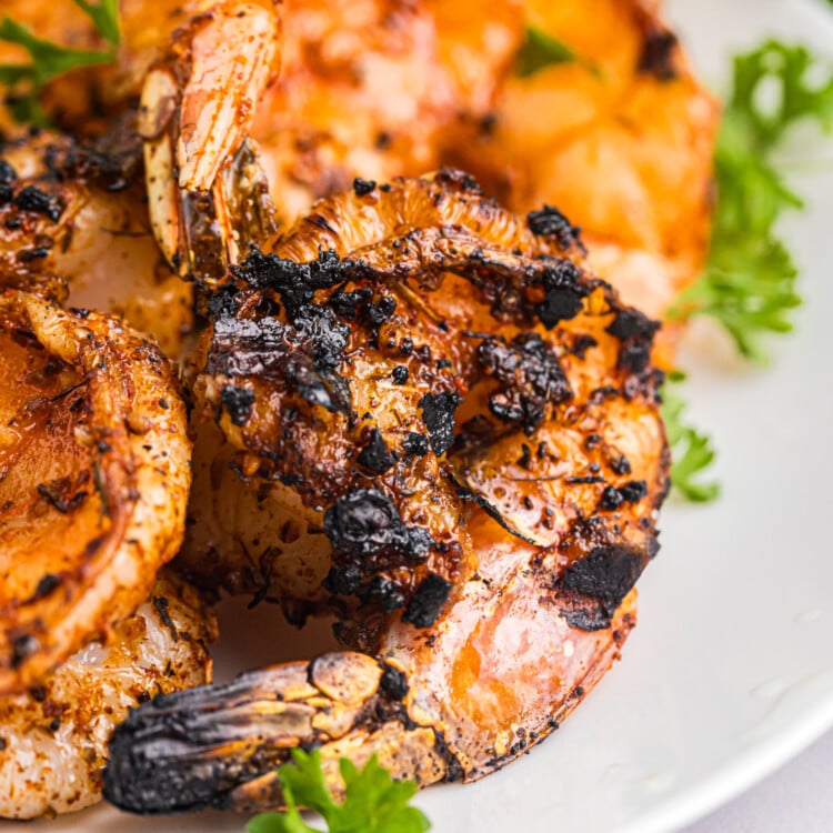 Juicy Cajun grilled shrimp with charred edges arranged on a plate, garnished with fresh parsley and lemon.