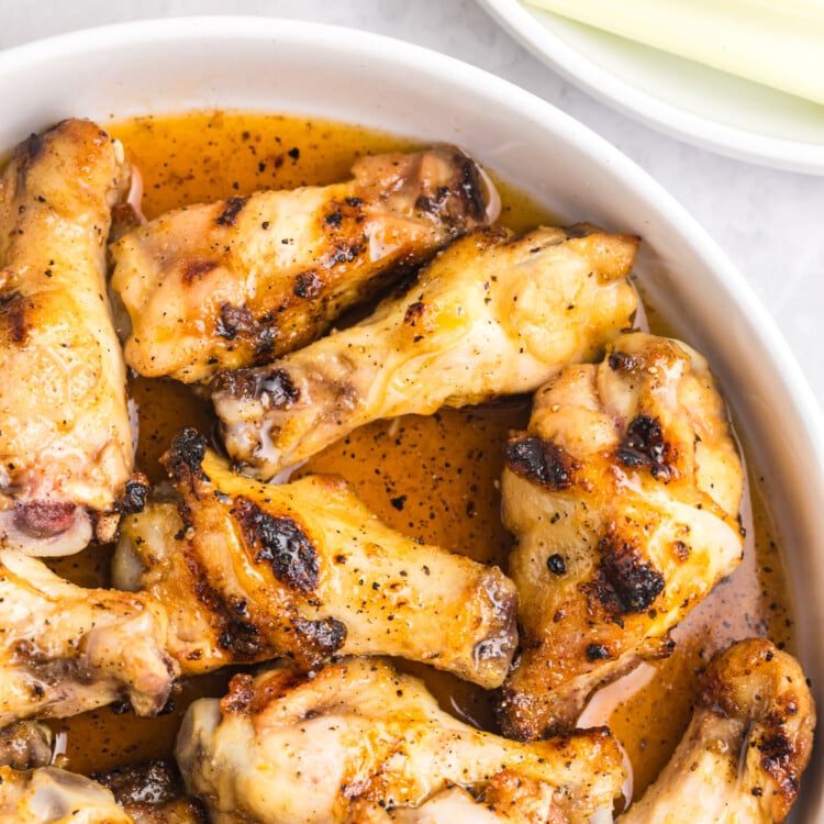 Close-up view of chicken wings glistening in hot honey sauce inside a white bowl.