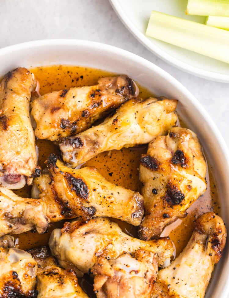 Close-up view of chicken wings glistening in hot honey sauce inside a white bowl.